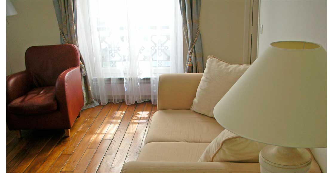Foto: Wohnzimmer mit Sofa, Stuhl und seidenen Vorhängen.